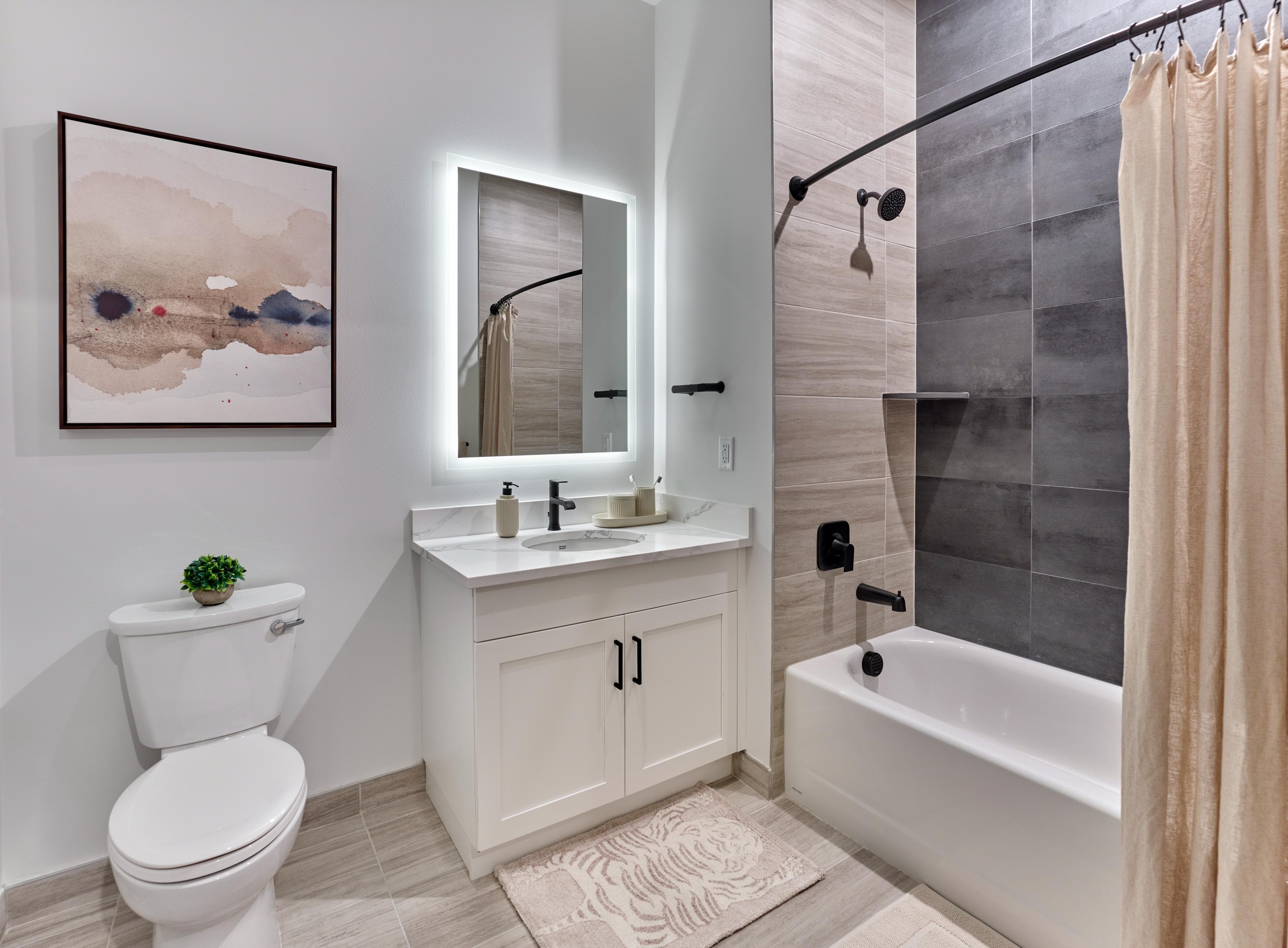 A bathroom with a white toilet, a sink with a mirror, and a bathtub with a shower curtain.