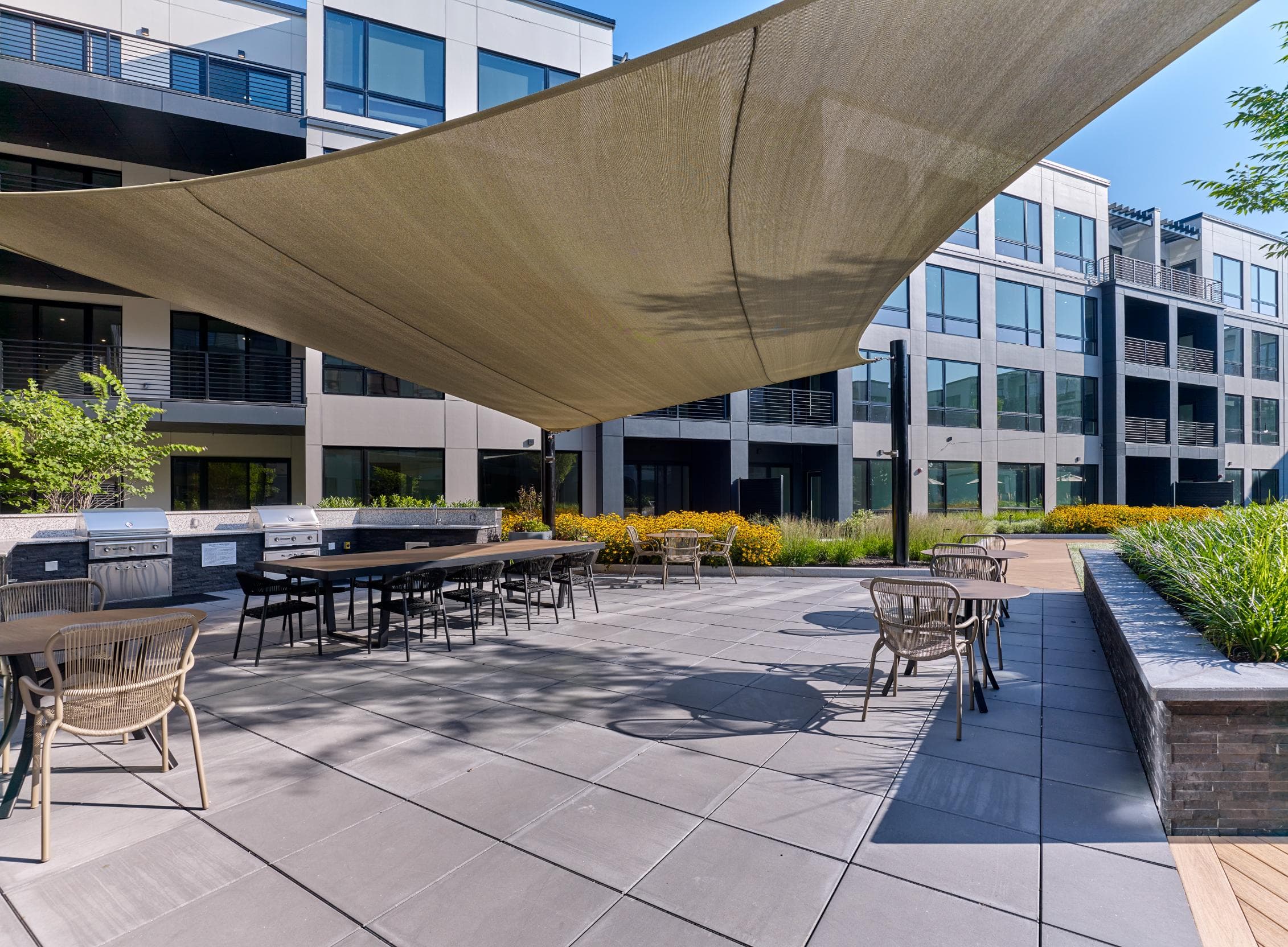 A patio with a table and chairs under a shade sail.