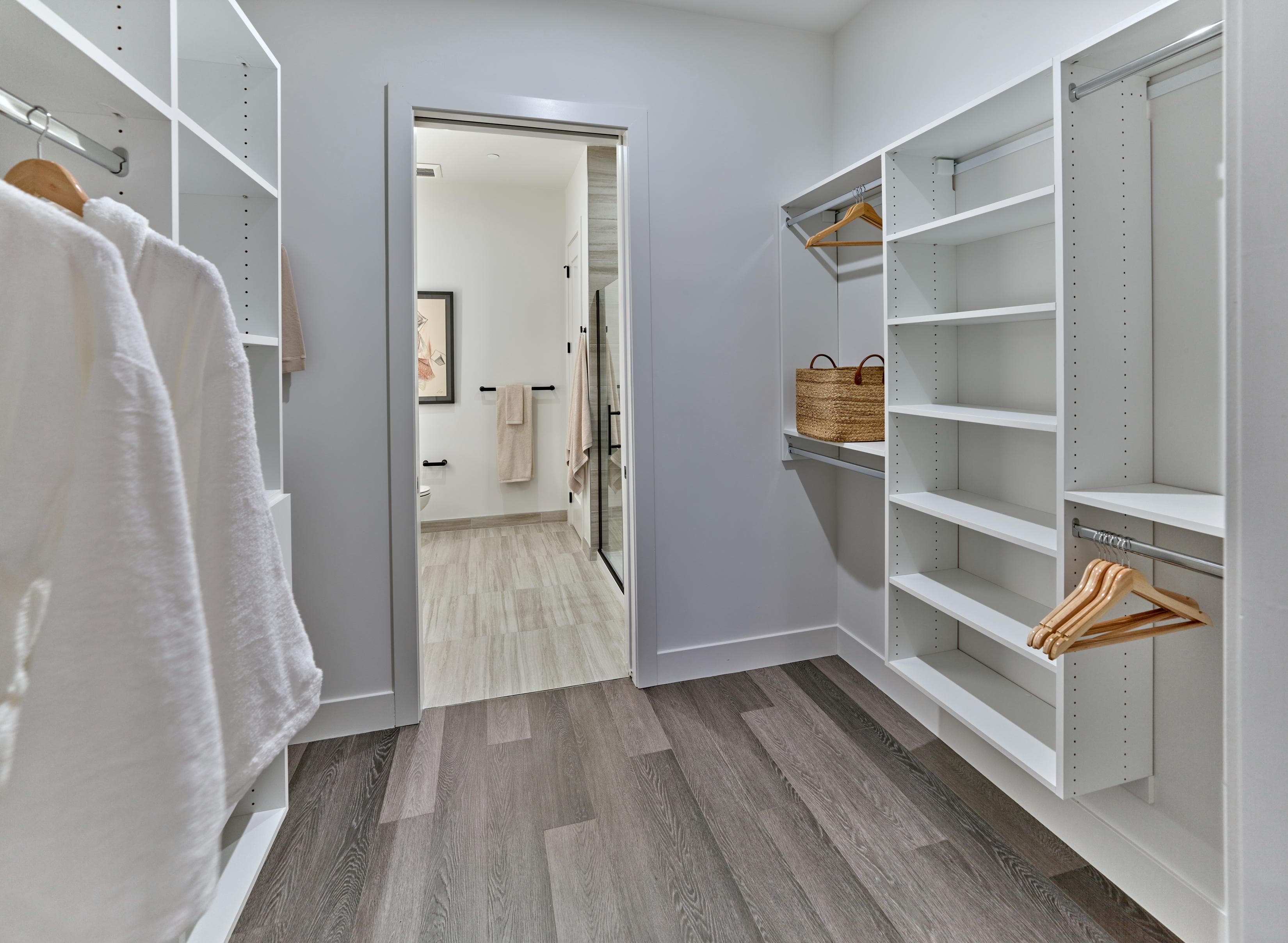 A white closet with a mirror and a brown basket on the shelf.