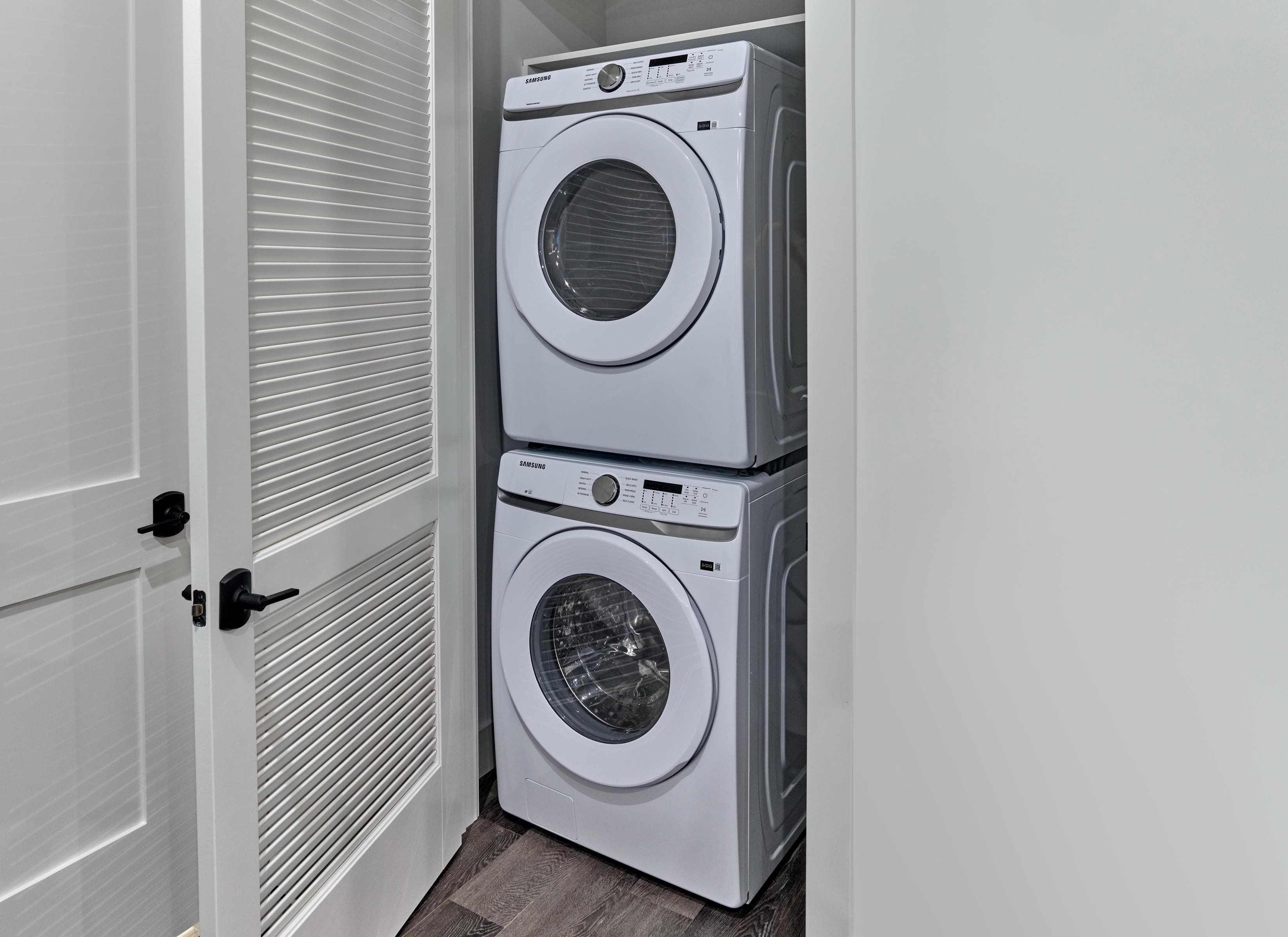 A white washing machine and dryer stacked on top of each other in a laundry room.