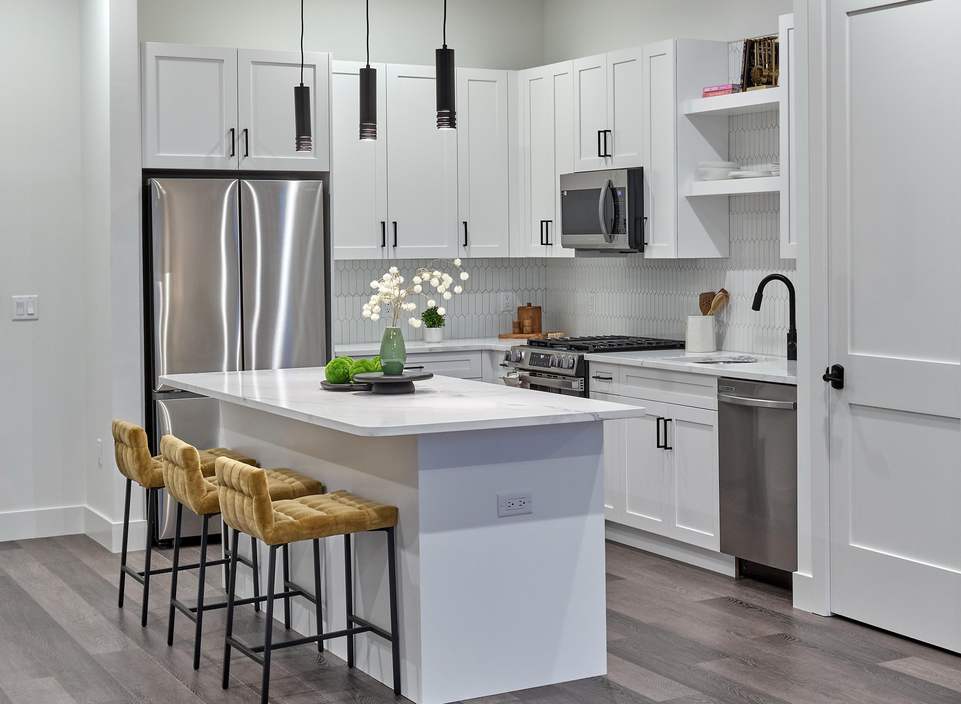 A modern kitchen with a white island and bar stools.