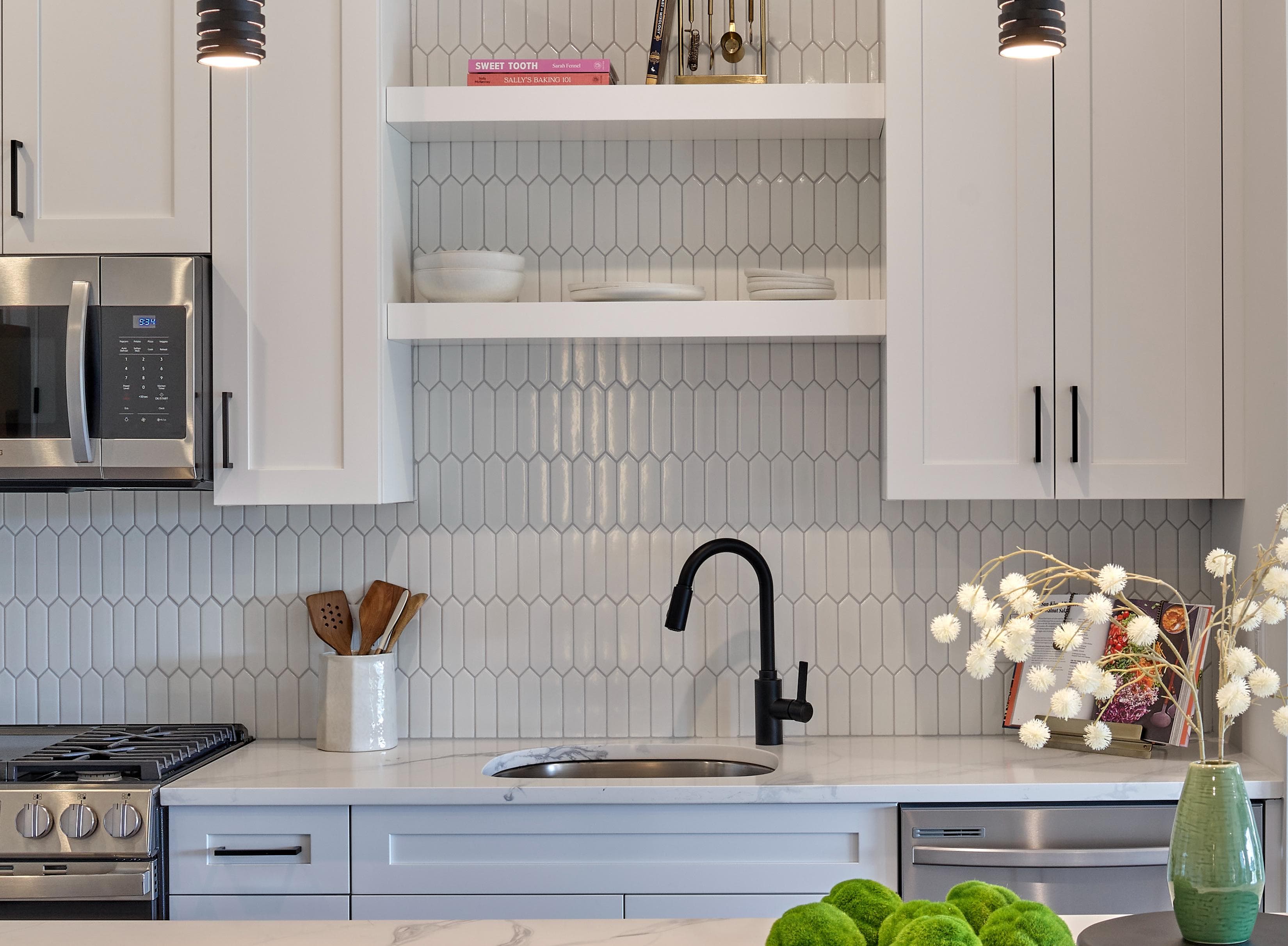 A kitchen with white cabinets and a black stove top.