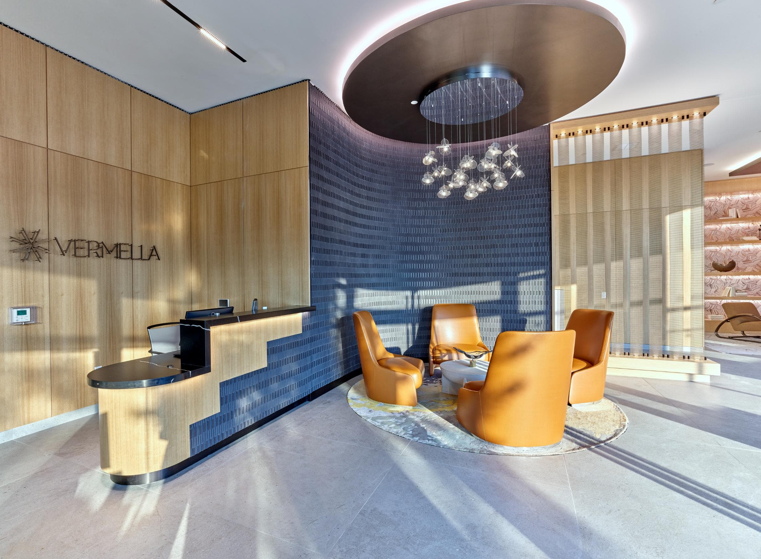 A reception area with orange chairs and a wooden counter.
