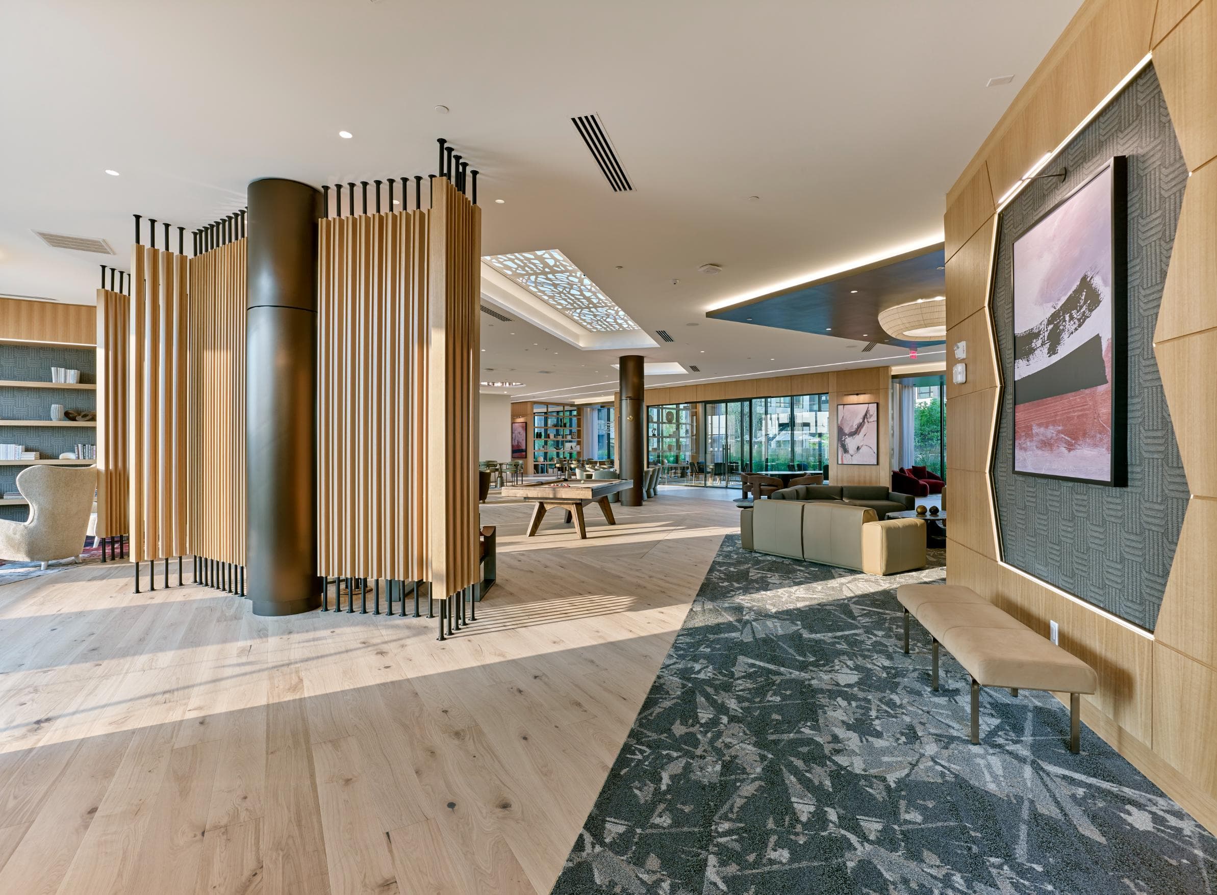 A modern office lobby with a wooden floor and a large screen on the right side.