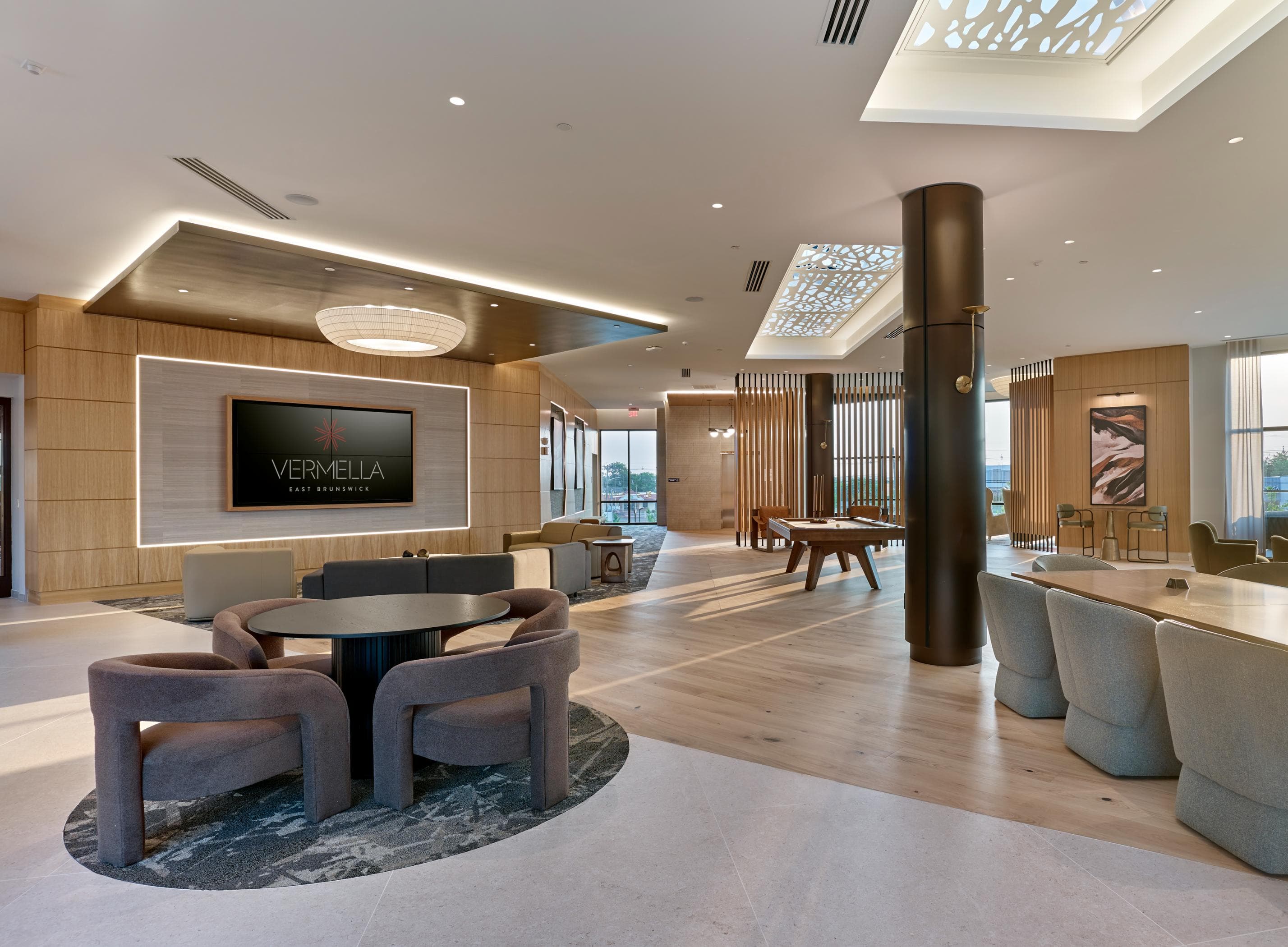 A modern living room with a round table and chairs, a flat screen TV, and a large window.