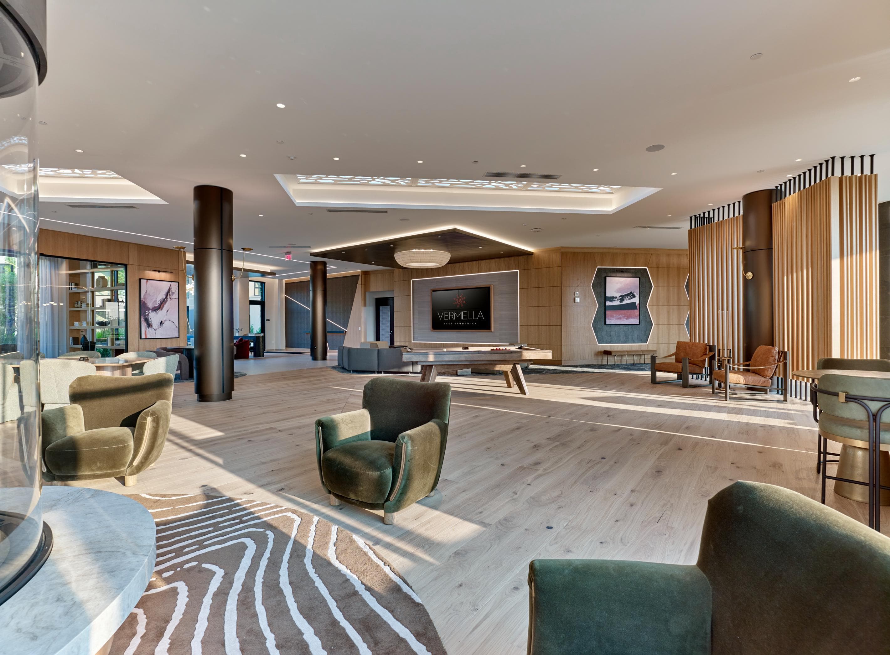 A large, modern living room with a variety of seating options and a flat-screen TV.