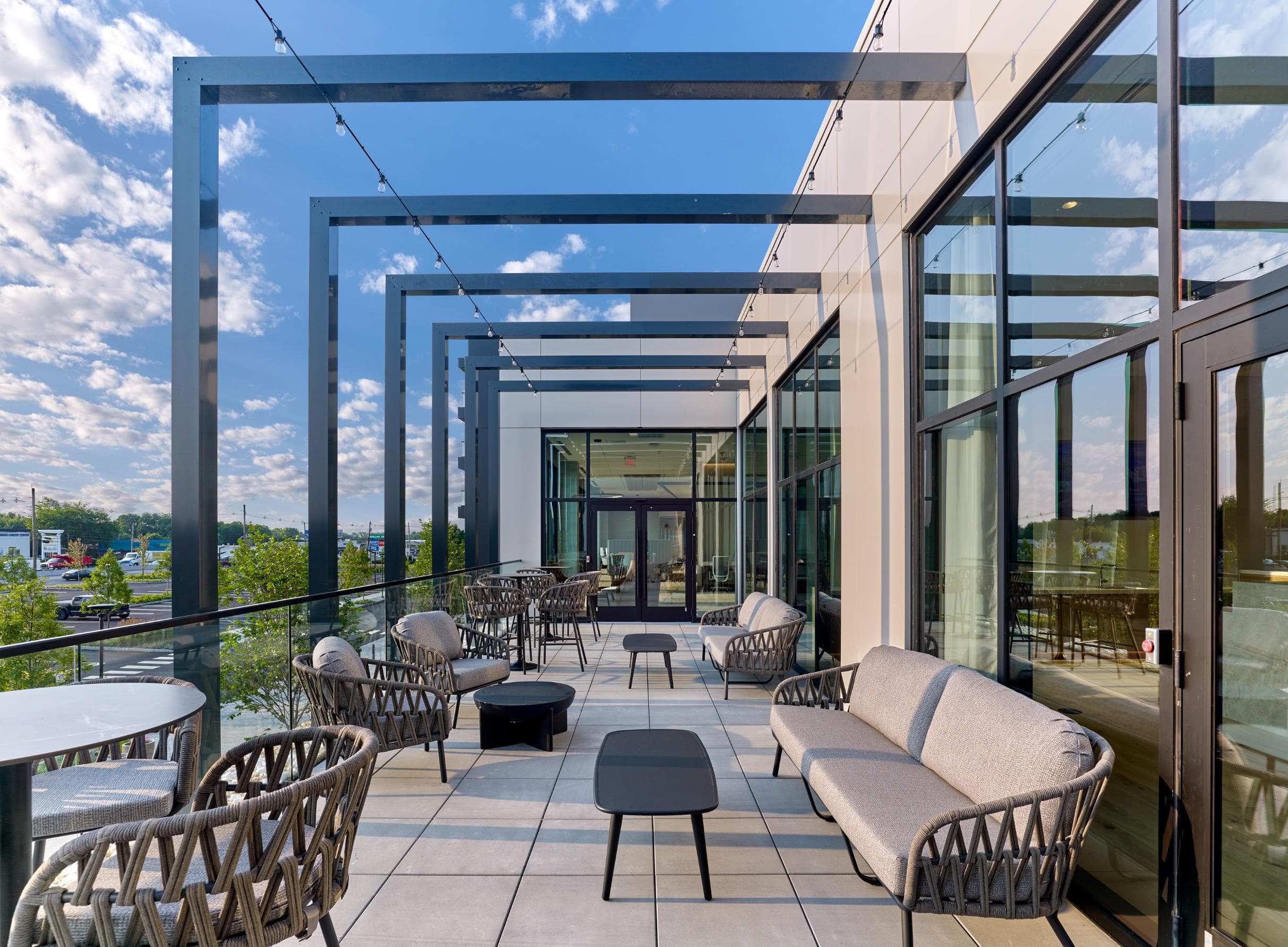 A modern outdoor seating area with wicker chairs and tables.