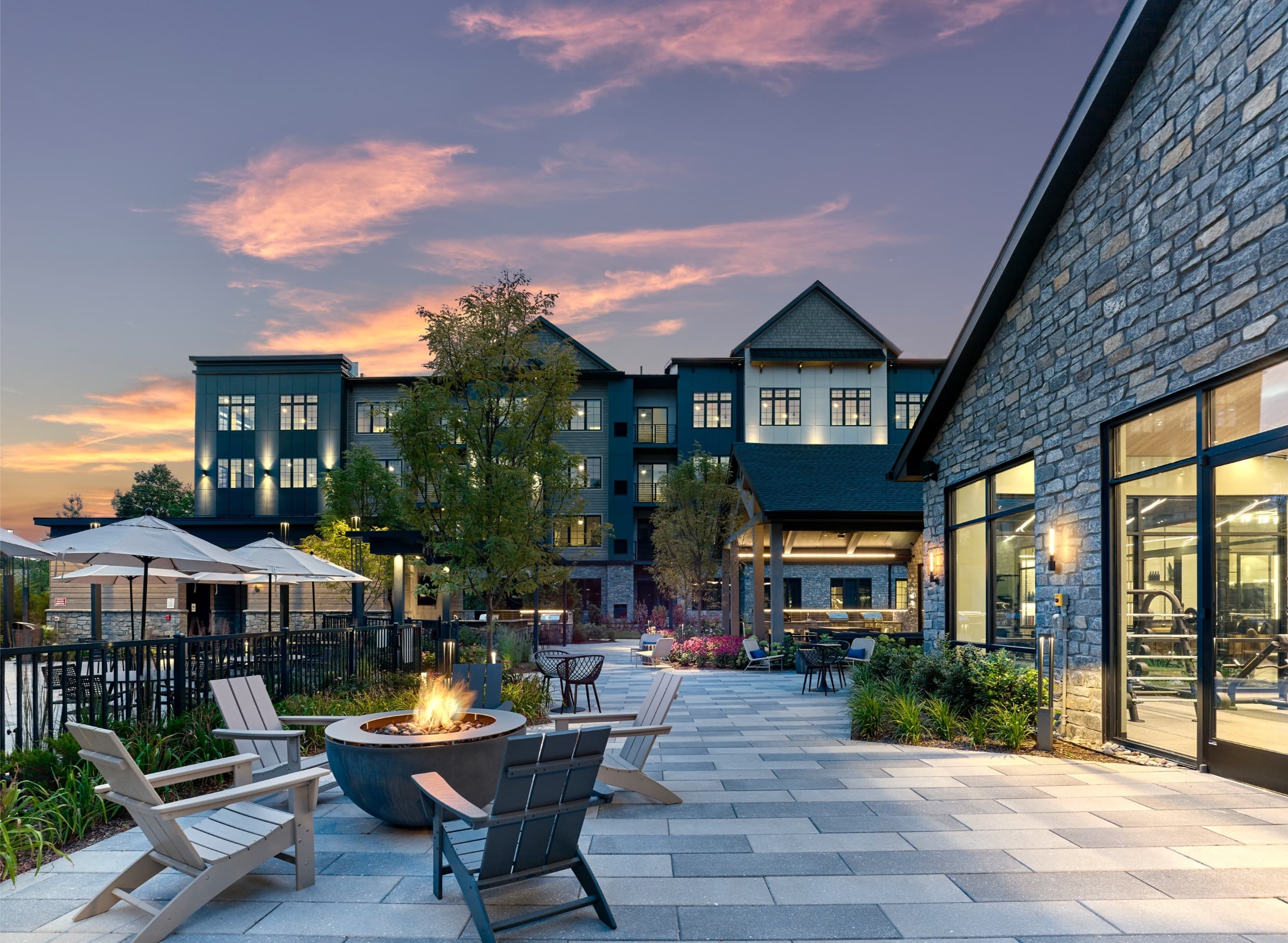 A patio with chairs and a fire pit in front of a building.