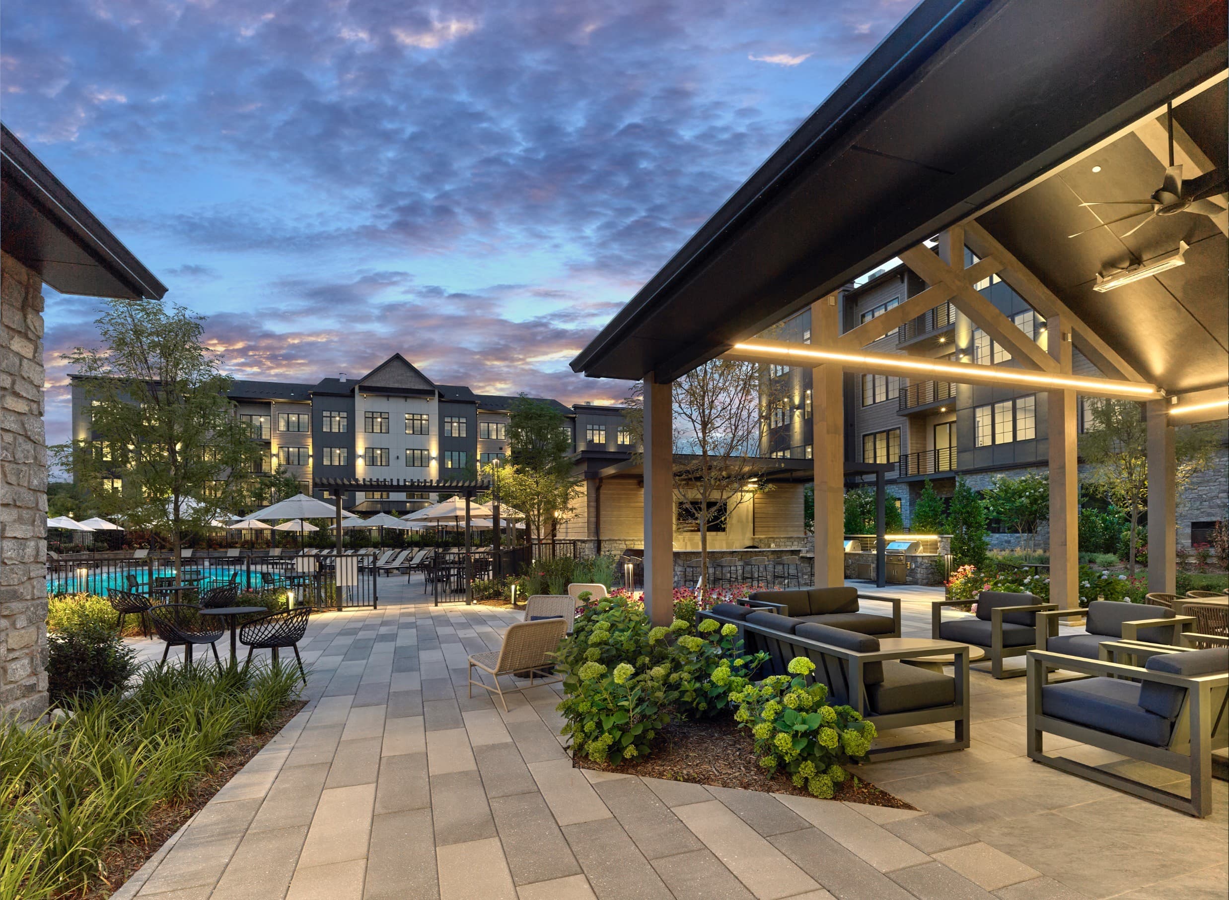 A patio area with a pool and a building in the background.
