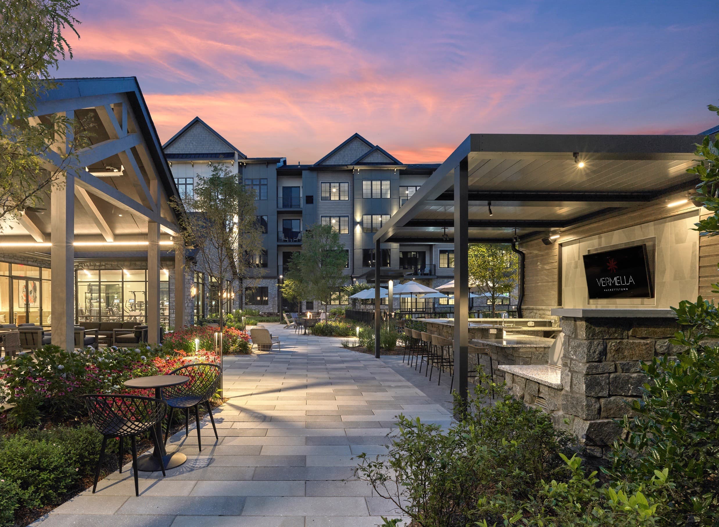 A patio with tables and chairs is surrounded by buildings.