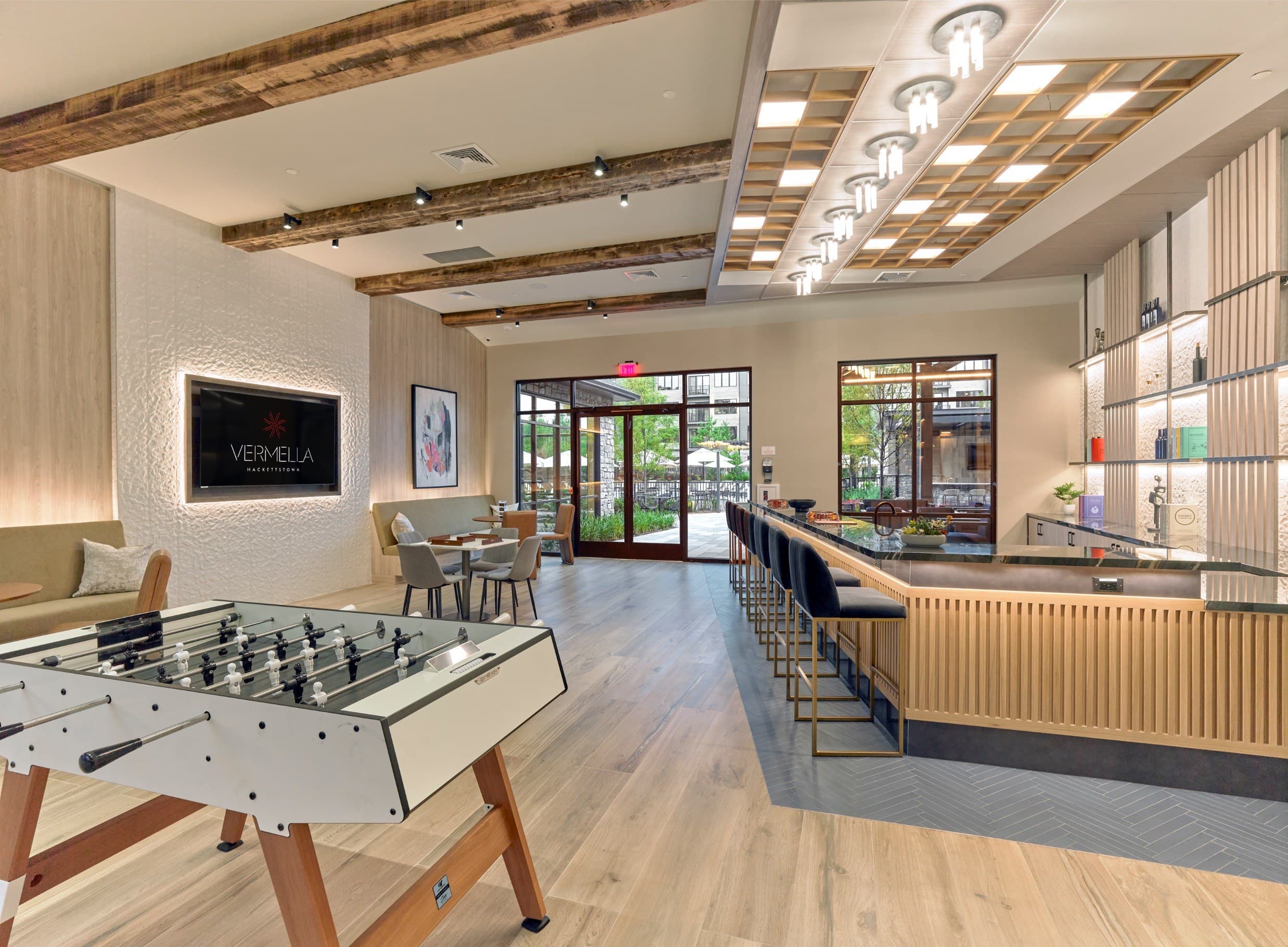 A foosball table is in the middle of a room with a bar and a couch.