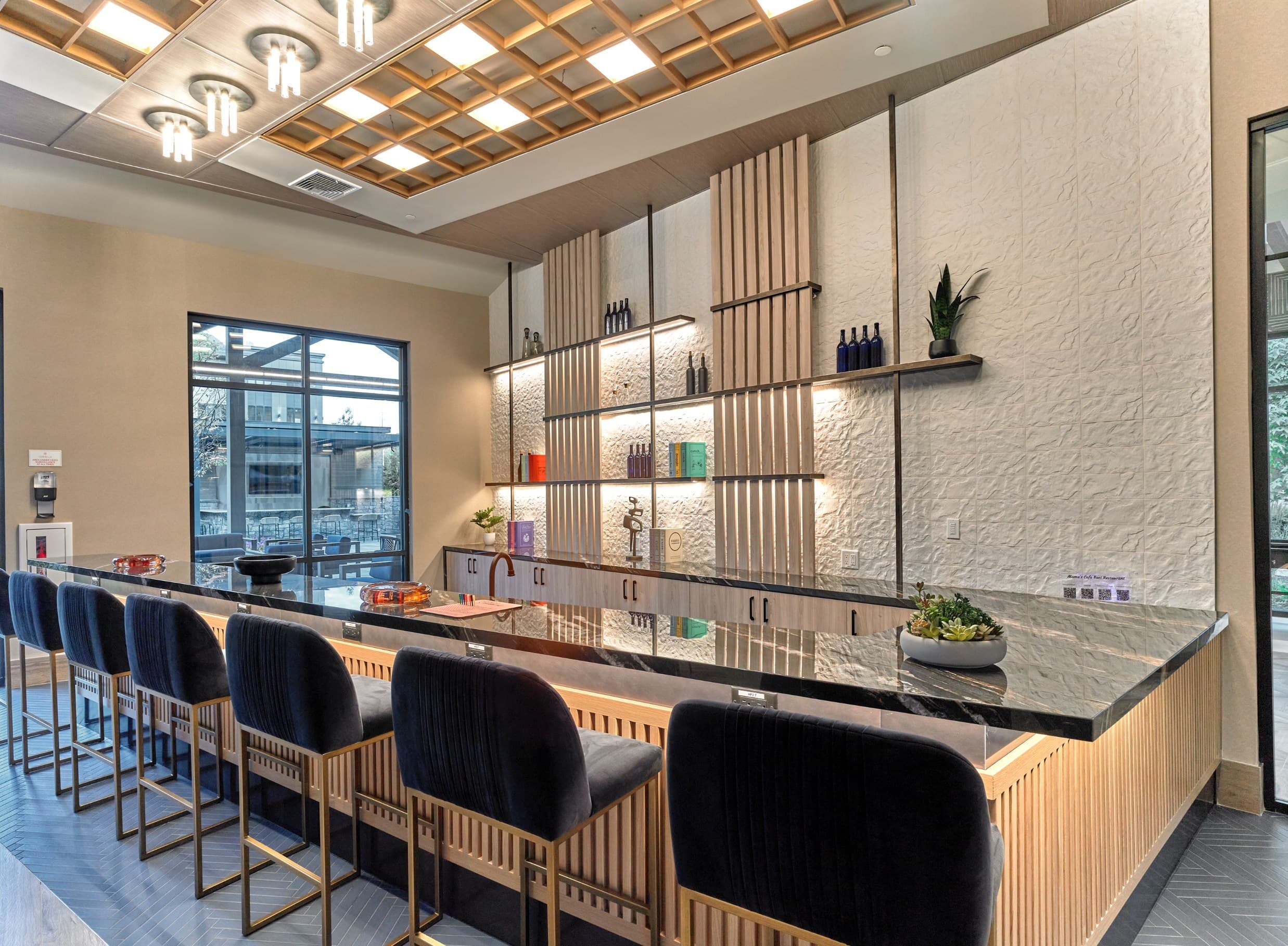 A long bar with black chairs and a wooden counter.