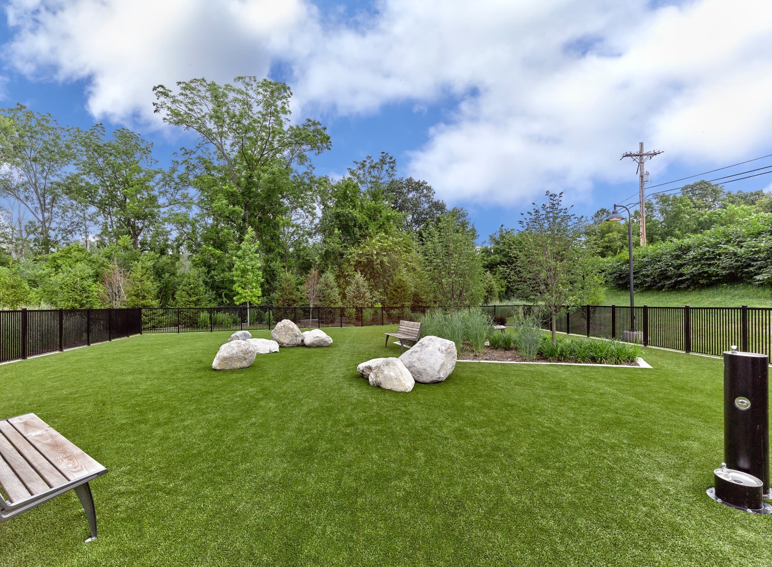 A backyard with a wooden bench and a green lawn.