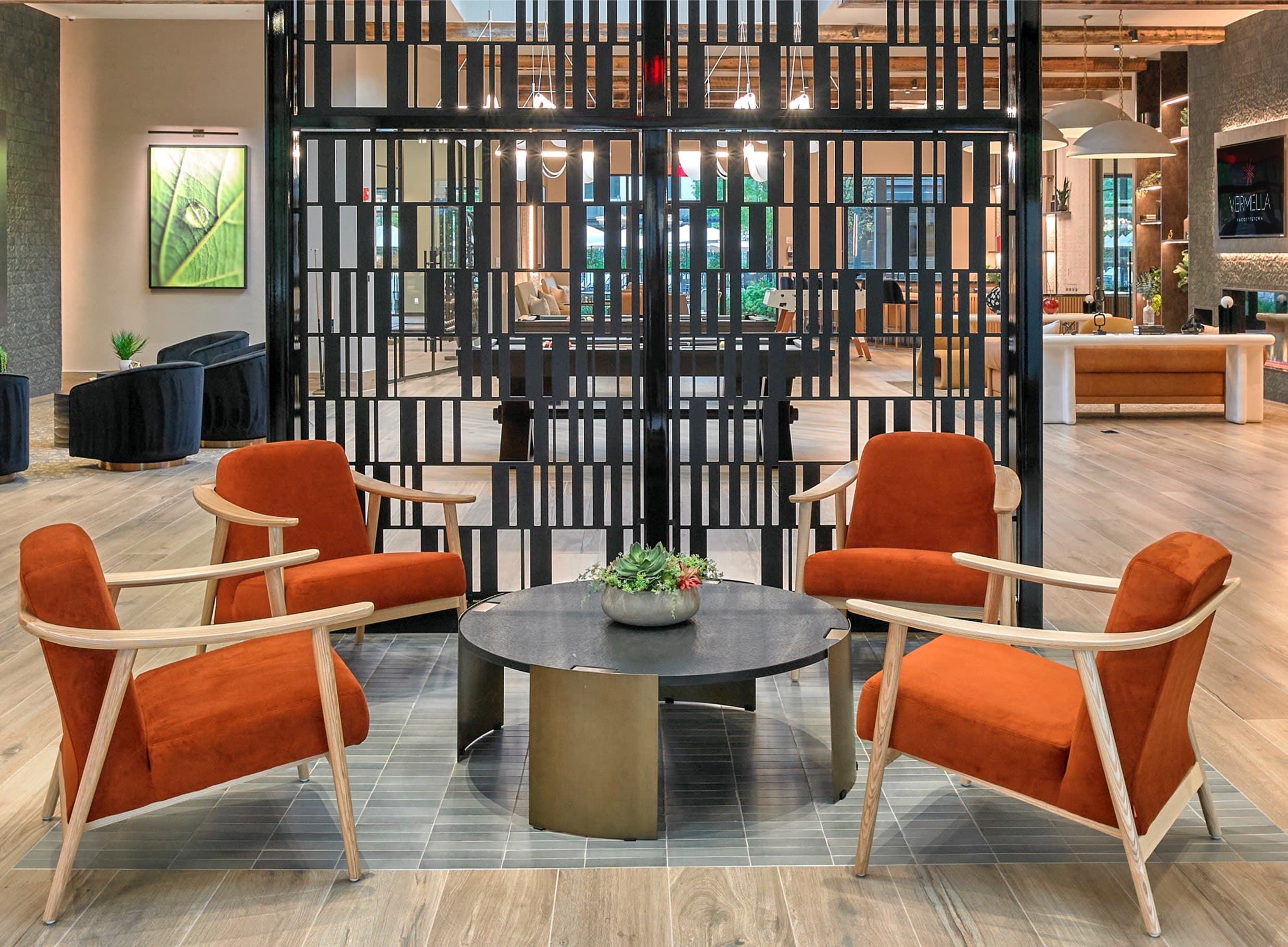 A black gate divides a room with orange chairs and a table.