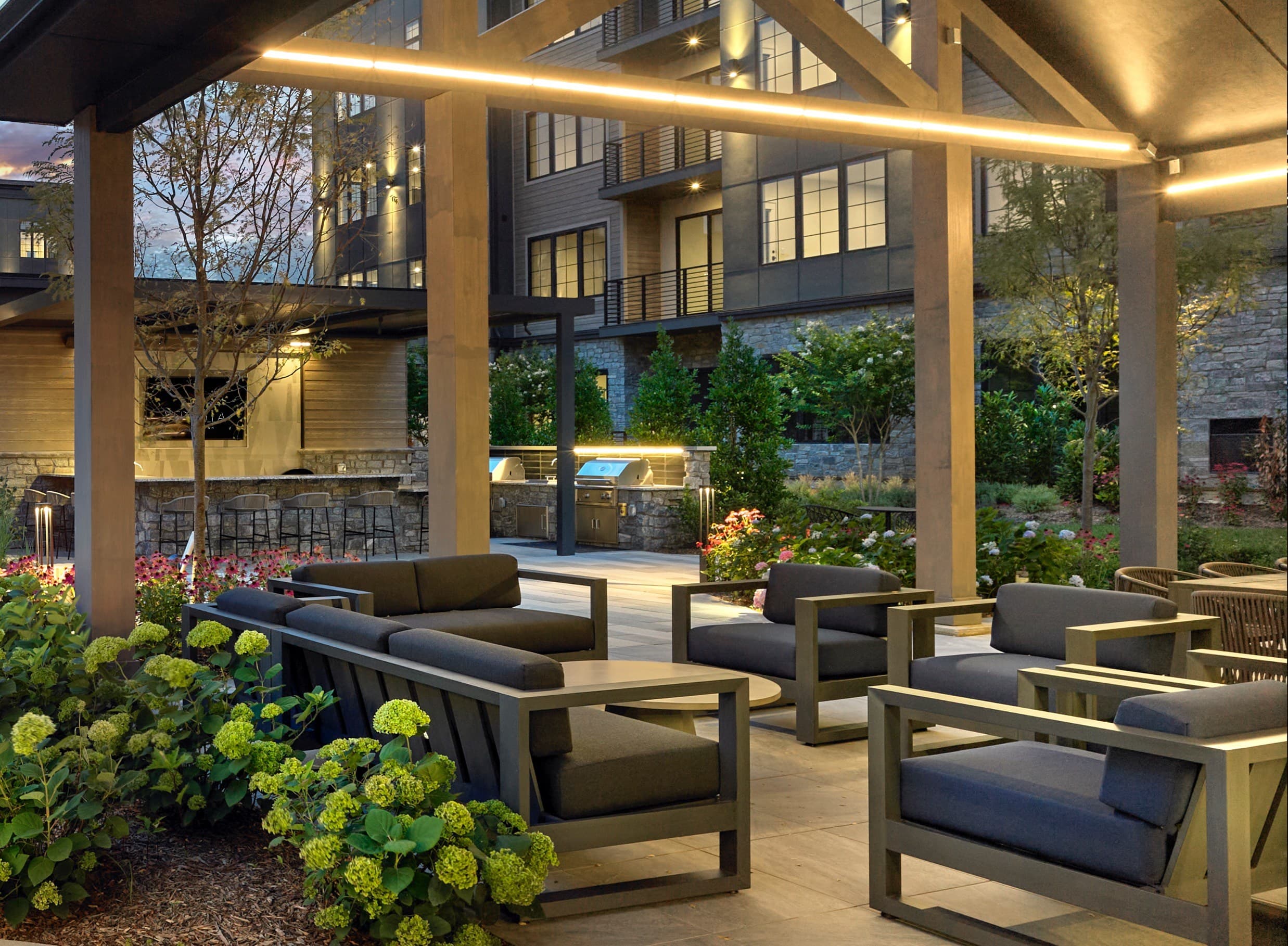 A patio with a table and chairs is lit by lights under a roof.