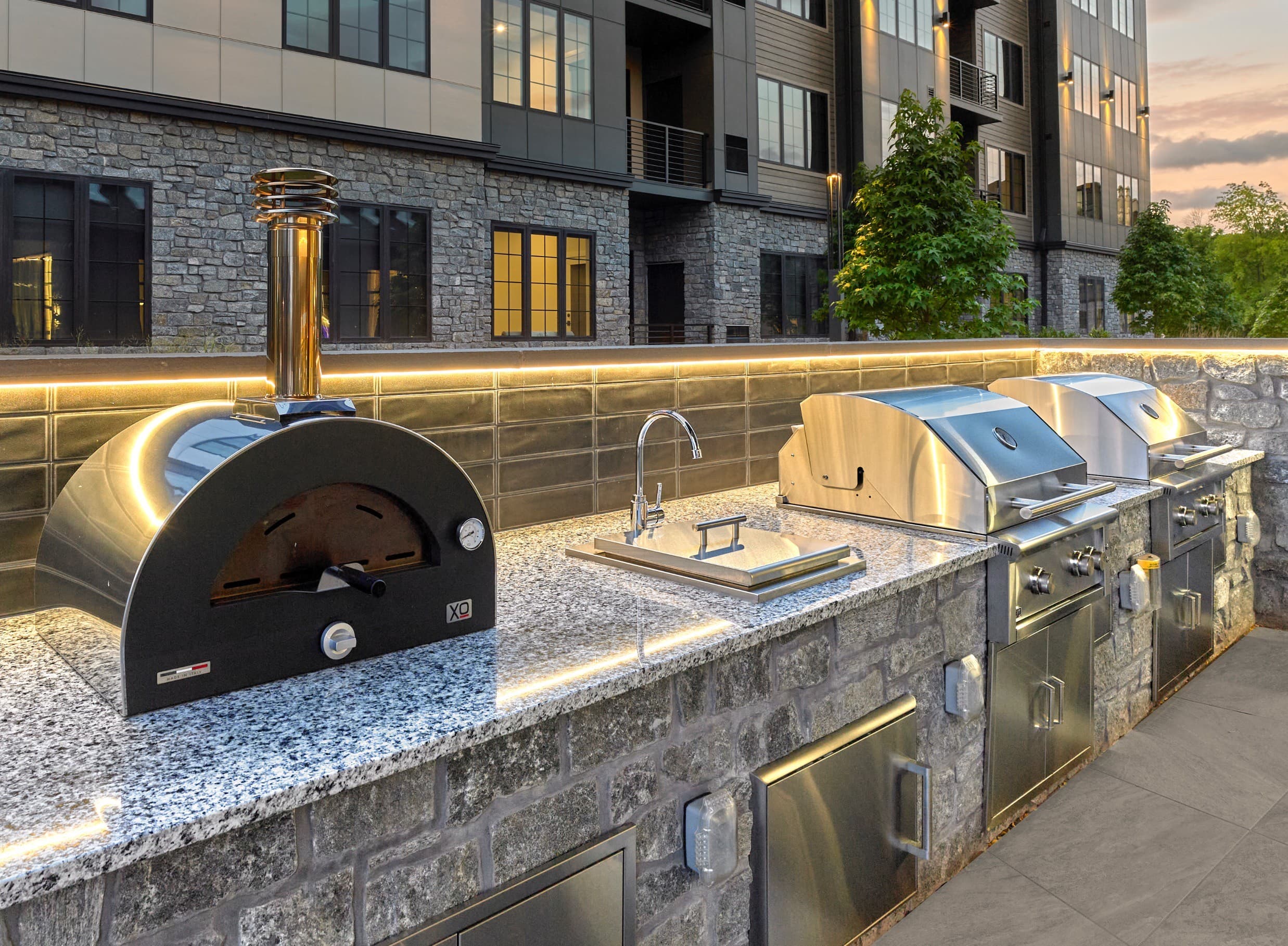 A stone oven is on a countertop next to a stainless steel oven.