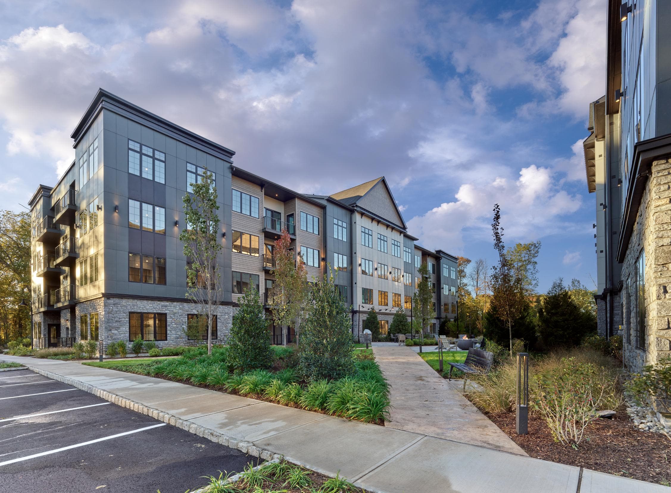 A modern apartment complex with a parking lot in front.