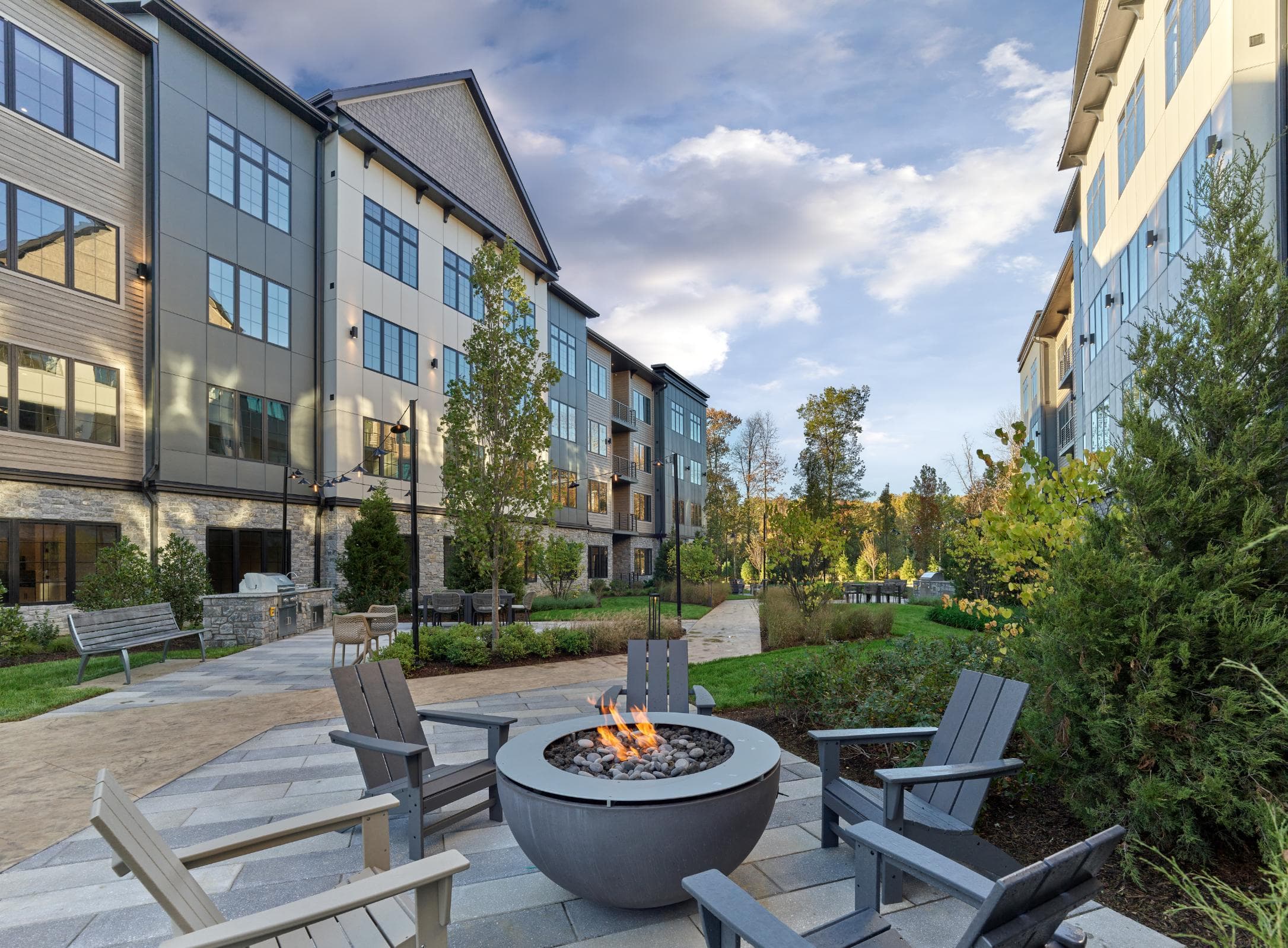 A fire pit sits in the middle of a patio surrounded by chairs.